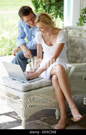 Couple using laptop together on patio Stock Photo
