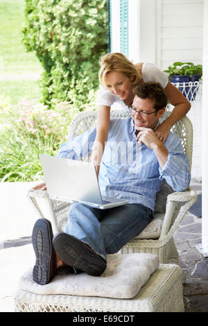 Couple using laptop together on patio Stock Photo
