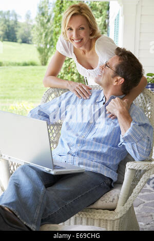 Couple using laptop together on patio Stock Photo