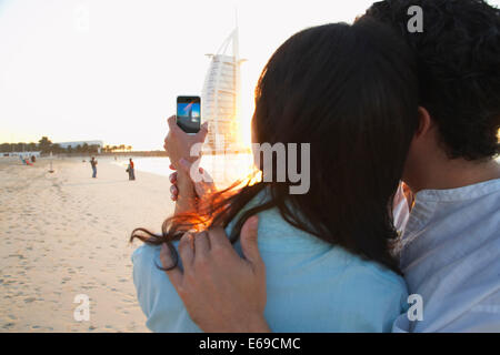 Couple taking pictures together on beach, Dubai, United Arab Emirates Stock Photo