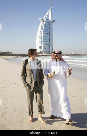 Businessmen walking on beach, Dubai, United Arab Emirates Stock Photo