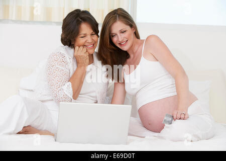 Mother and pregnant daughter using laptop Stock Photo