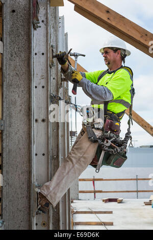 Caucasian worker hammering nails at construction site Stock Photo