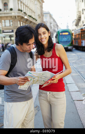 Couple reading map on city street Stock Photo