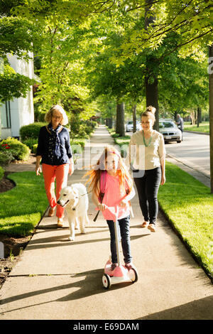 Caucasian family walking dog on suburban sidewalk Stock Photo