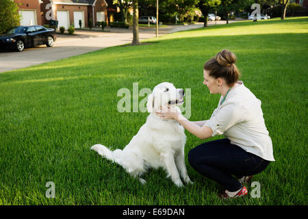 Caucasian woman petting dog in park Stock Photo