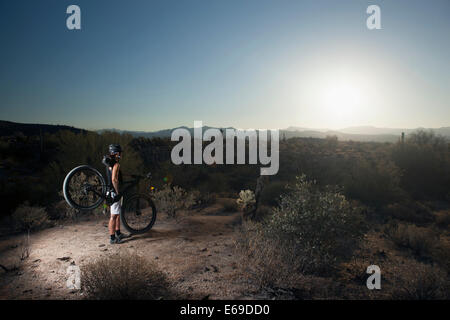 Mountain biker standing in desert Stock Photo