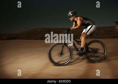 Woman riding mountain bike in desert Stock Photo