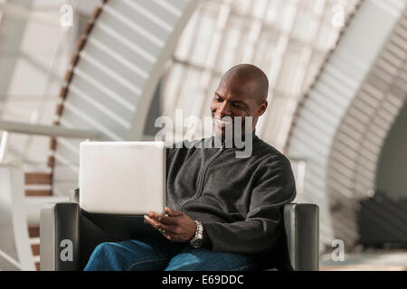 African American man using laptop in lobby Stock Photo