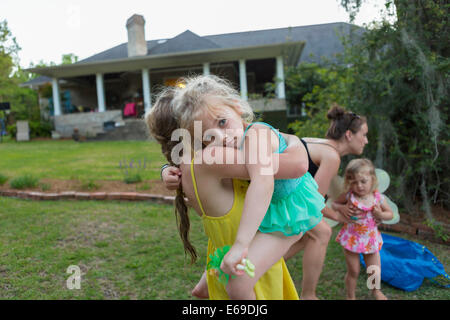 Girl carrying sister outdoors Stock Photo
