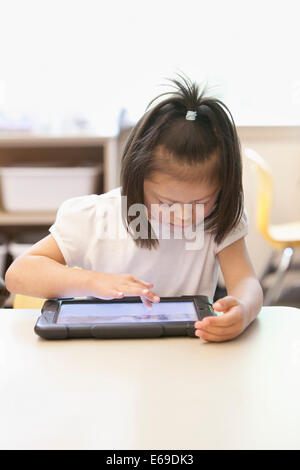 Mixed race Down syndrome student using tablet computer in classroom Stock Photo
