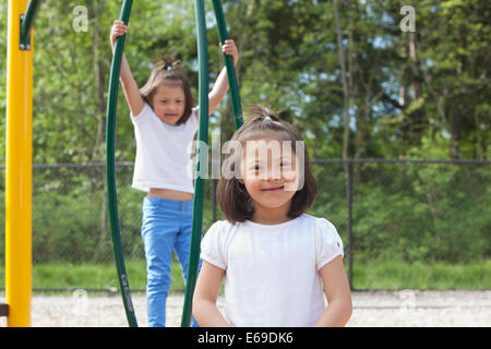 Mixed race Down syndrome girls smiling on playground Stock Photo