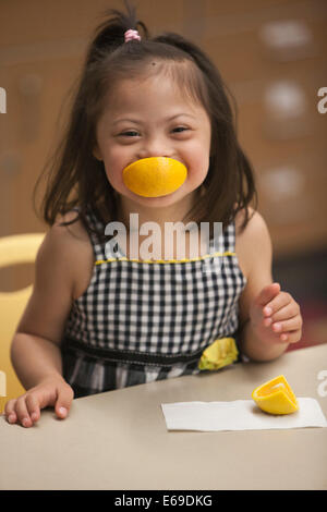 Mixed race girl with Down syndrome eating fruit Stock Photo