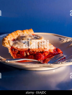 A slice of homemade cherry pie on a white plate with fork. Stock Photo