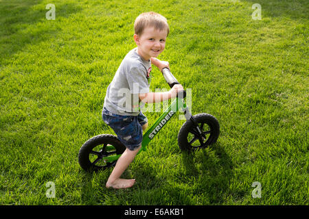 Small Boy Smiling at Camera, Sitting on His Bicycle in Backyard,  USA Stock Photo
