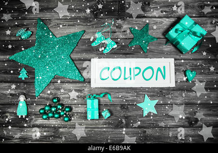 Christmas presents: white wooden sign for xmas message and green decoration on wooden background. Stock Photo