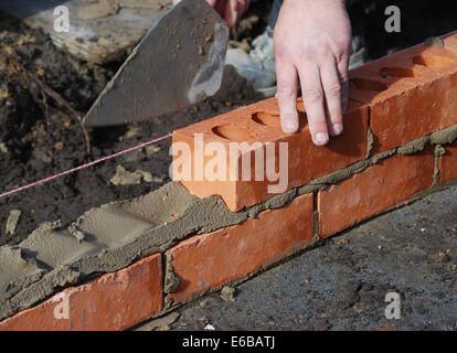 Construction worker laying bricks showing trowel and guideline. Stock Photo