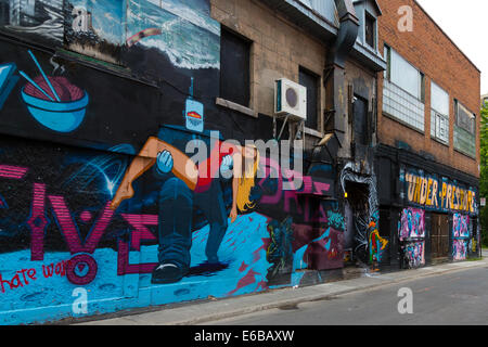 Graffiti on the side of a building in Montreal, Canada showing a robot in a suit carrying an unconscious blond woman in a red Stock Photo