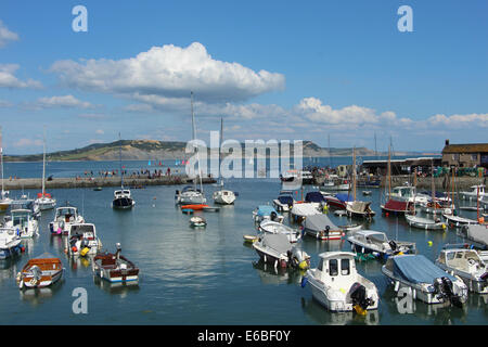 View from the Cobb at Lyme Regis looking east over the harbour on bright August day with blue sky and light white clouds Stock Photo