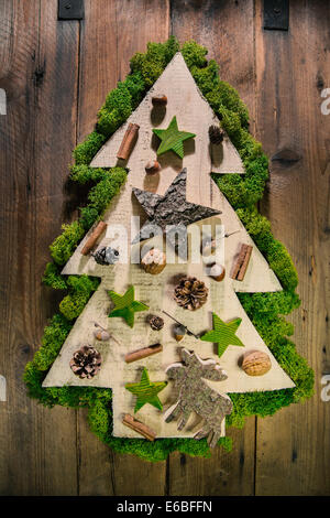 Handmade christmas tree of wood on wooden background with natural decoration of the forest. Stock Photo