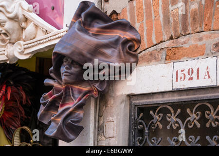 A leather Carnival wall mask sculpture hanging outside one of the main mask shops in Venice. Stock Photo