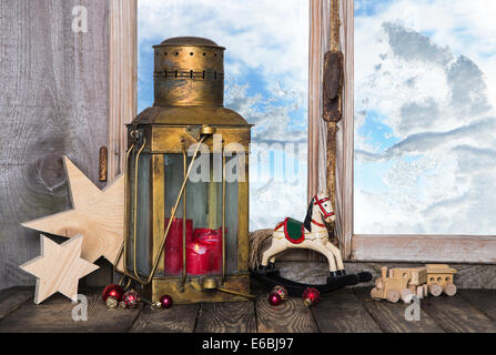 Nostalgic old christmas decoration with old toys and a old lantern with candles on the window sill. Stock Photo