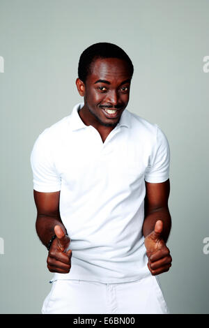 African man standing with thumbs up on gray background Stock Photo
