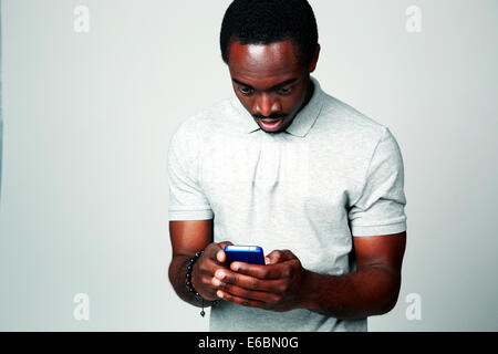 Surprised african man using smartphone on gray background Stock Photo