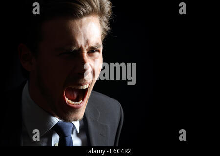 Angry businessman shouting isolated in a black background Stock Photo