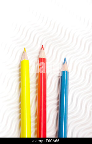 red, blue and yellow pencils on white corrugated paper Stock Photo