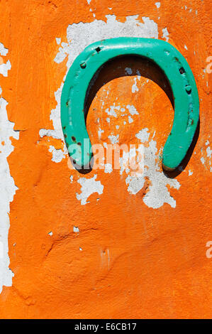 Green horseshoe decorating a peeling orange wall, France, Europe Stock Photo