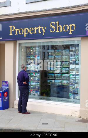 Man viewing property for sale in an estate agent's window