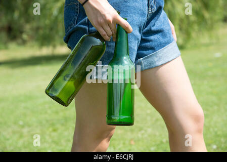 Woman's hand holding empty wine and beer bottles to be recycled Stock Photo