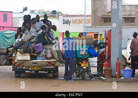 Men and luggage piled on a pick up at a gas station in Gulu,  Northern Uganda. The vehicles are filling up with fuel.