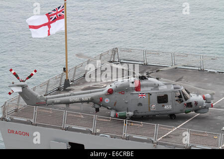 Helicopter on deck of ship. Westland Lynx HMA8 military aircraft on the stern of the Royal Navy destroyer HMS Dragon beneath a flying White Ensign Stock Photo