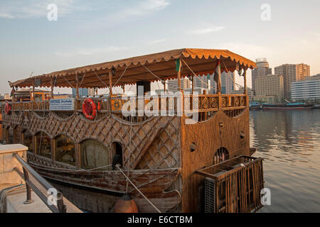 Old wooden dhow with decorative carving used as floating restaurant on calm waters of Dubai Creek in heart of city of  Dubai UAE Stock Photo