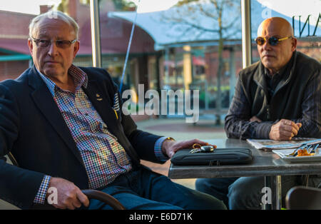 Two middle aged gentlemen having coffee seated at cafe Stock Photo