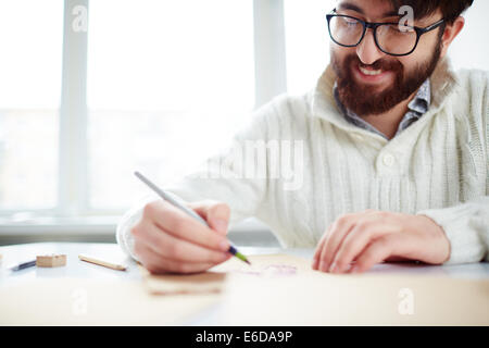 Image of happy young man in eyeglasses drawing Stock Photo