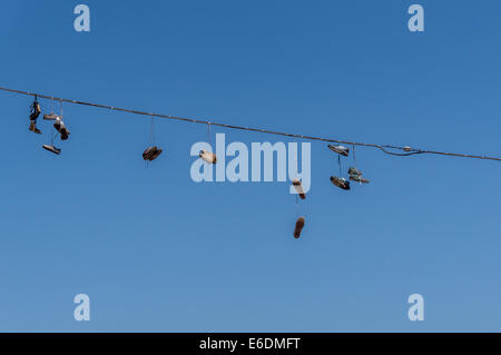Pairs of shoes hanging from overhead wire. Shoefiti. Stock Photo