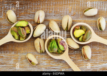 Pistachio nuts on wooden spoons on wooden surface Stock Photo