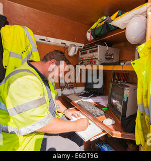 A worker writes a report about the footage in his van from a remote control camera with wheels which drives up the sewer pipes c Stock Photo