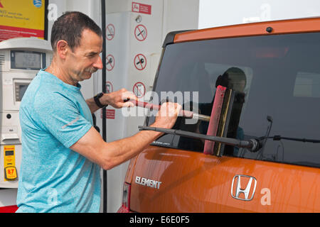 Man washing glass vehicle windshield at service station in Canada Stock Photo