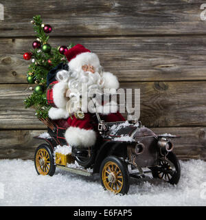 Santa claus in rush with his car: christmas shopping stress. Decoration with old vintage tin toys on wooden background. Stock Photo