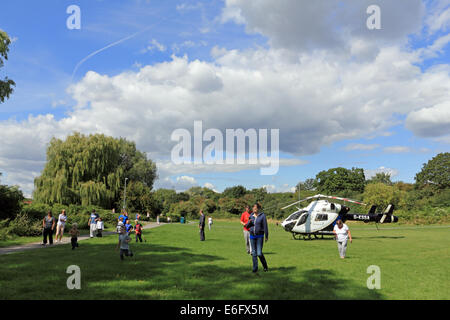 West Ewell, Epsom, Surrey, UK. 22nd Aug, 2014. Residents of West Ewell had a suprise this afternoon as the KSSA (Kent Surrey Sussex Air ambulance) landed on an area of the Hogsmill Open Space between Riverview School and the Watersedge Estate. It landed at 13.30 in response to 'A medical Emergency' on the estate. Locals gathered to see the unusual site of a helicopter so close to nearby housing, and as it was summer holiday time many curious childern were keen to witness the event. Credit:  Julia Gavin UK/Alamy Live News Stock Photo