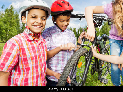 Smiling African boys in helmets repair bike Stock Photo