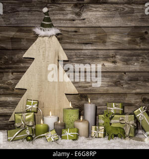 Natural christmas decoration in green and brown on wooden background with presents and burning candles. Stock Photo