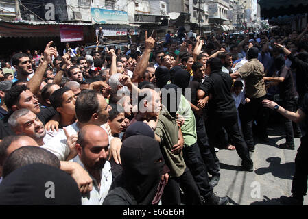 Gaza. 22nd Aug, 2014. Palestinian citizens and Hamas gunmen gather at the scene of a public execution of Palestinians suspected of collaborating with Israel in a street in downtown Gaza City on Aug. 22, 2014. Masked Gaza militants executed 18 Palestinians on Friday who were convicted of collaborating with Israel in Gaza City, pro-Hamas al-Aqsa TV reported. Credit:  Yasser Qudih/Xinhua/Alamy Live News Stock Photo