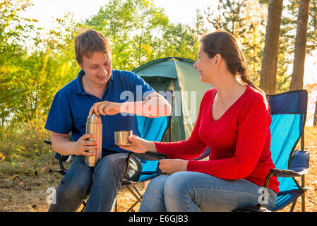 family drinking tea next to the tent near Pine Stock Photo