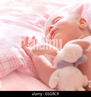 Newborn baby sleeps, relaxing in the bed, adorable healthy child dreaming, safe childhood concept Stock Photo