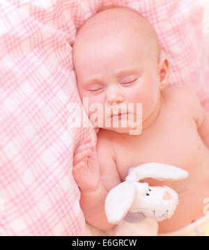 Cute baby asleep in pink bedroom, relaxing in the bed, adorable healthy child dreaming, safe childhood concept Stock Photo